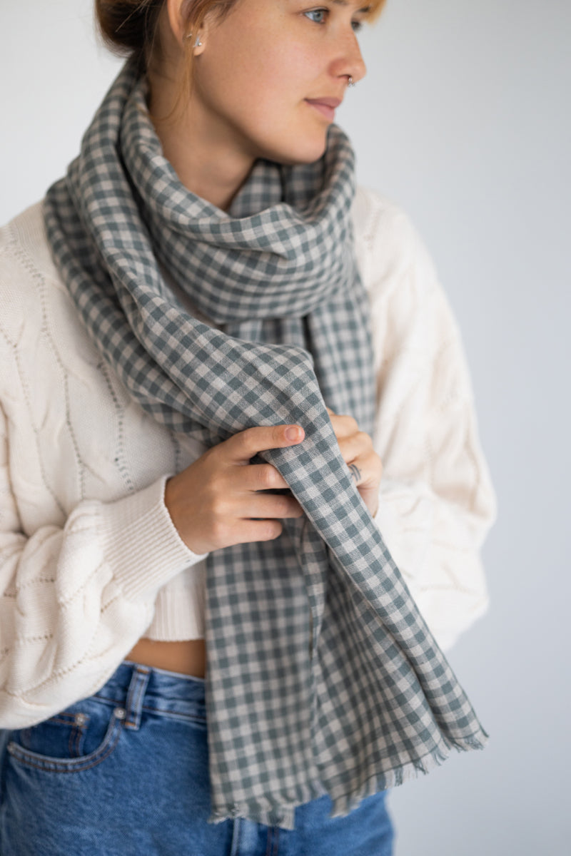 Woman wearing a plaid linen scarf with a plain background

