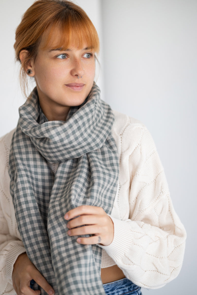 Woman wearing a gray checkered linen scarf against a white background

