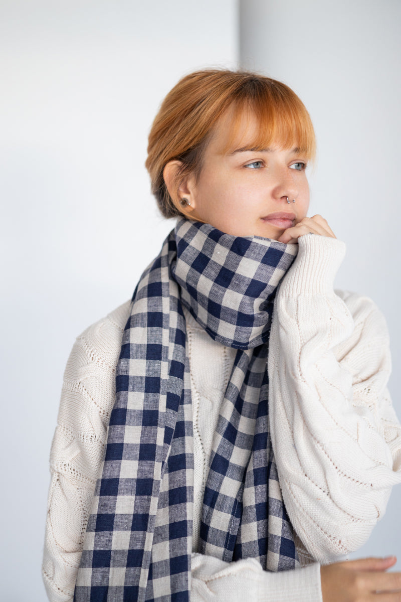 Person wearing a blue and white checkered linen scarf with a plain background