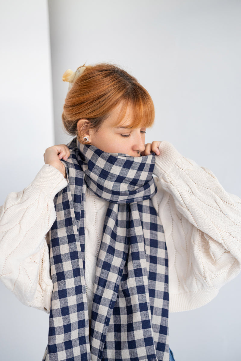 Person wearing a blue and white checkered linen scarf with a plain background