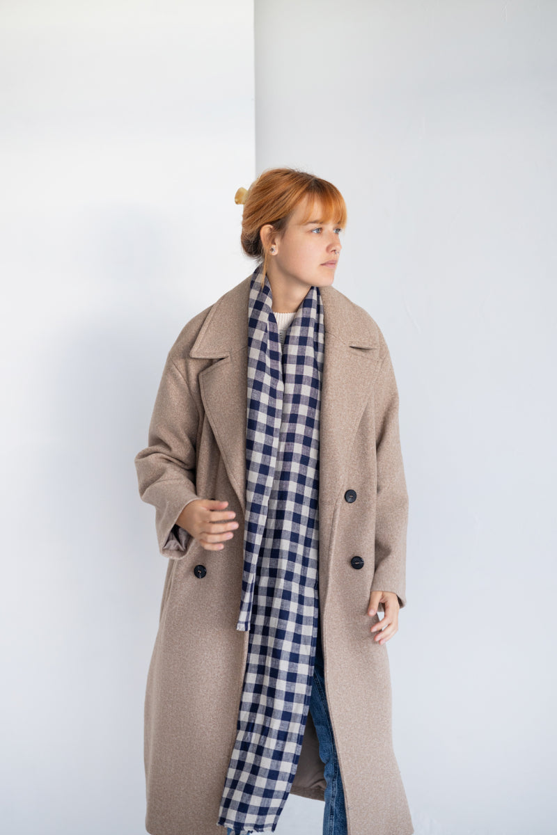 Person wearing a blue and white checkered linen scarf with a plain background