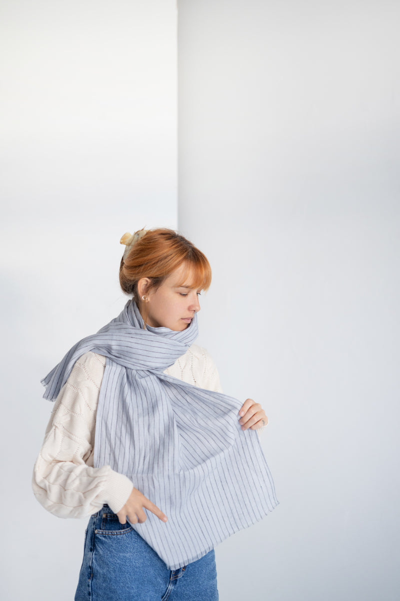 Person wearing a long coat and light gray linen scarf against a white background