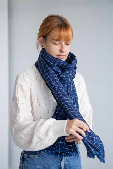 Women wearing a blue checkered linen scarf against a plain background
