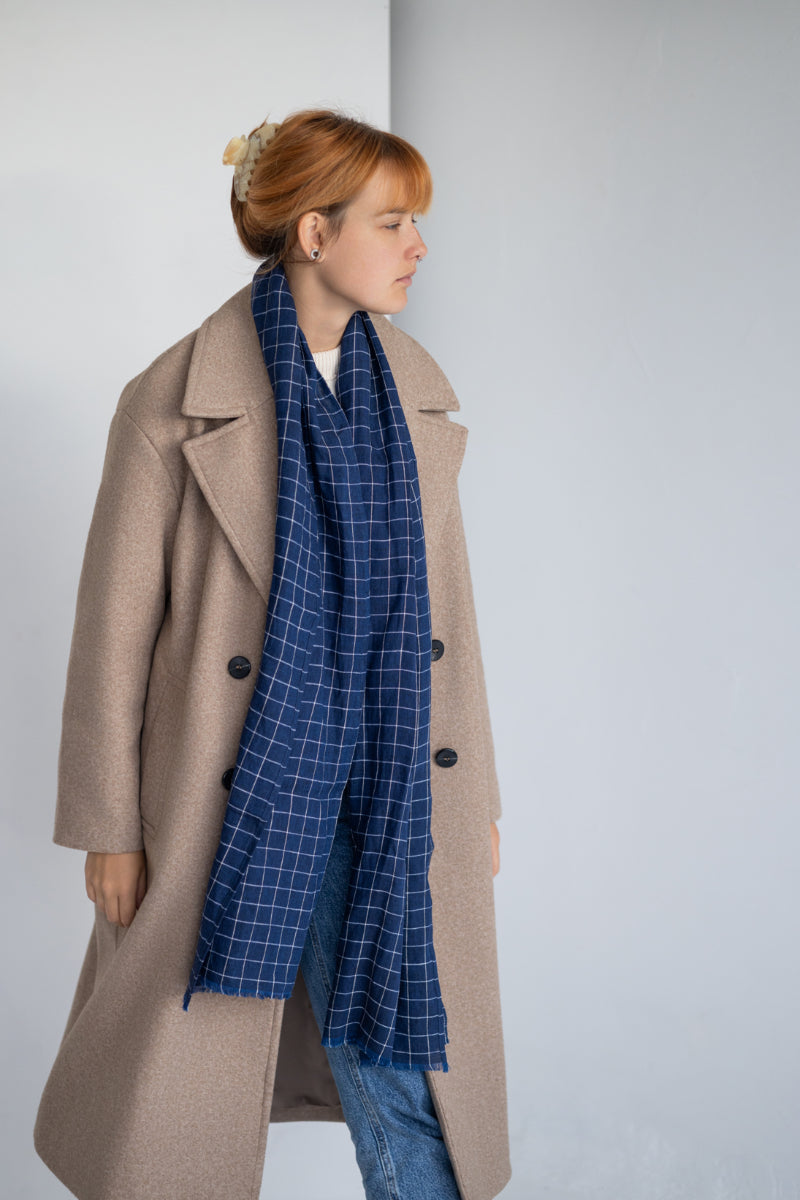 Women wearing a blue checkered linen scarf against a plain background
