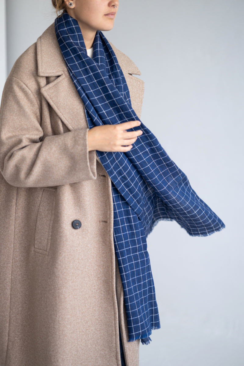Women wearing a blue checkered linen scarf against a plain background

